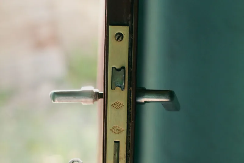Puerta entreabierta con manilla metálica y un juego de llaves en el cilindro.